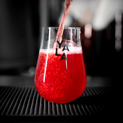 Red drink being poured into a glass with 'YALA' branding on a blurred background